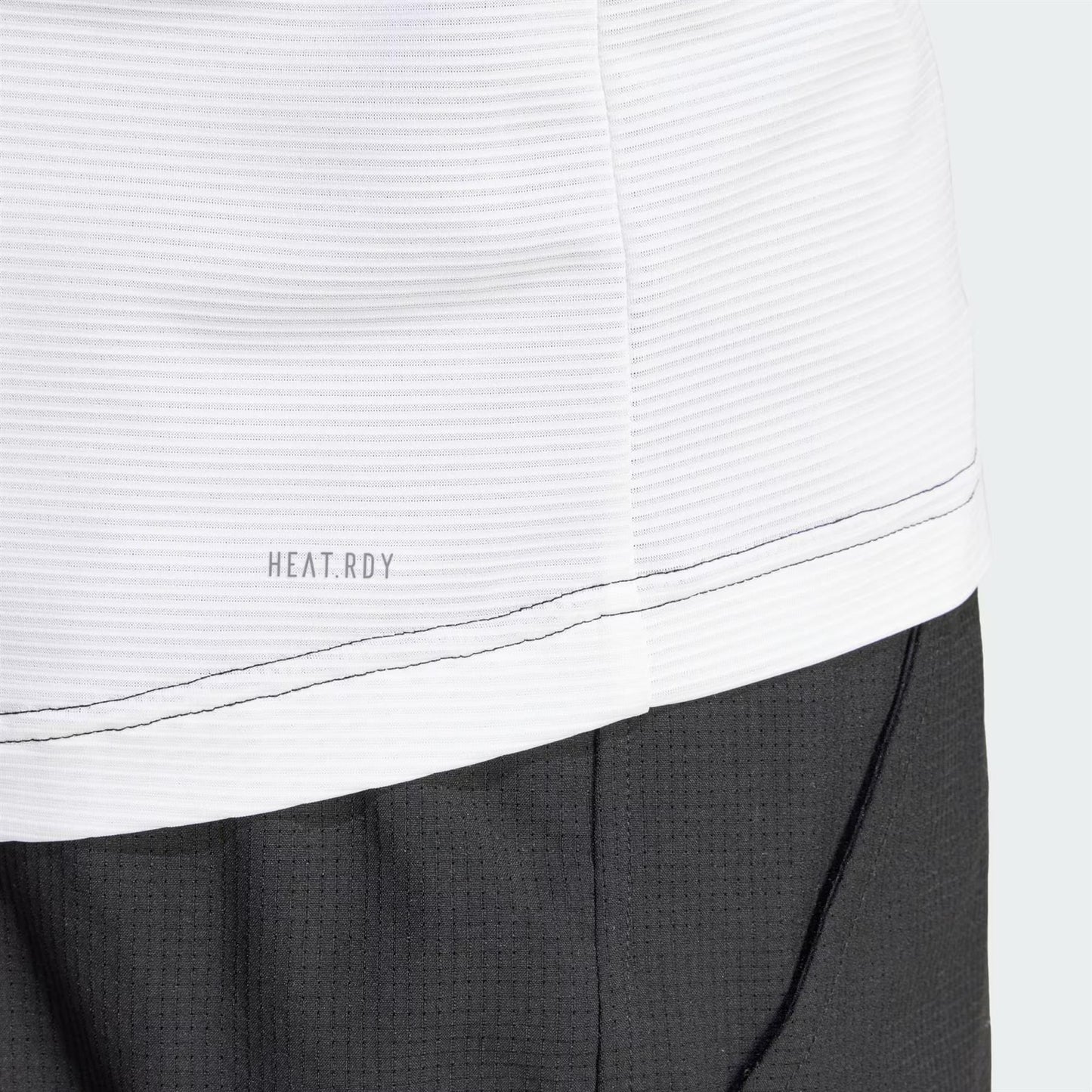 A close-up of the adidas Mens Pro Freelift 3D Tennis T-Shirt in Black/White features a white ribbed texture labeled "HEAT.RDY technology" on top, seamlessly transitioning into a black textured fabric beneath, elegantly divided by a stitched seam.
