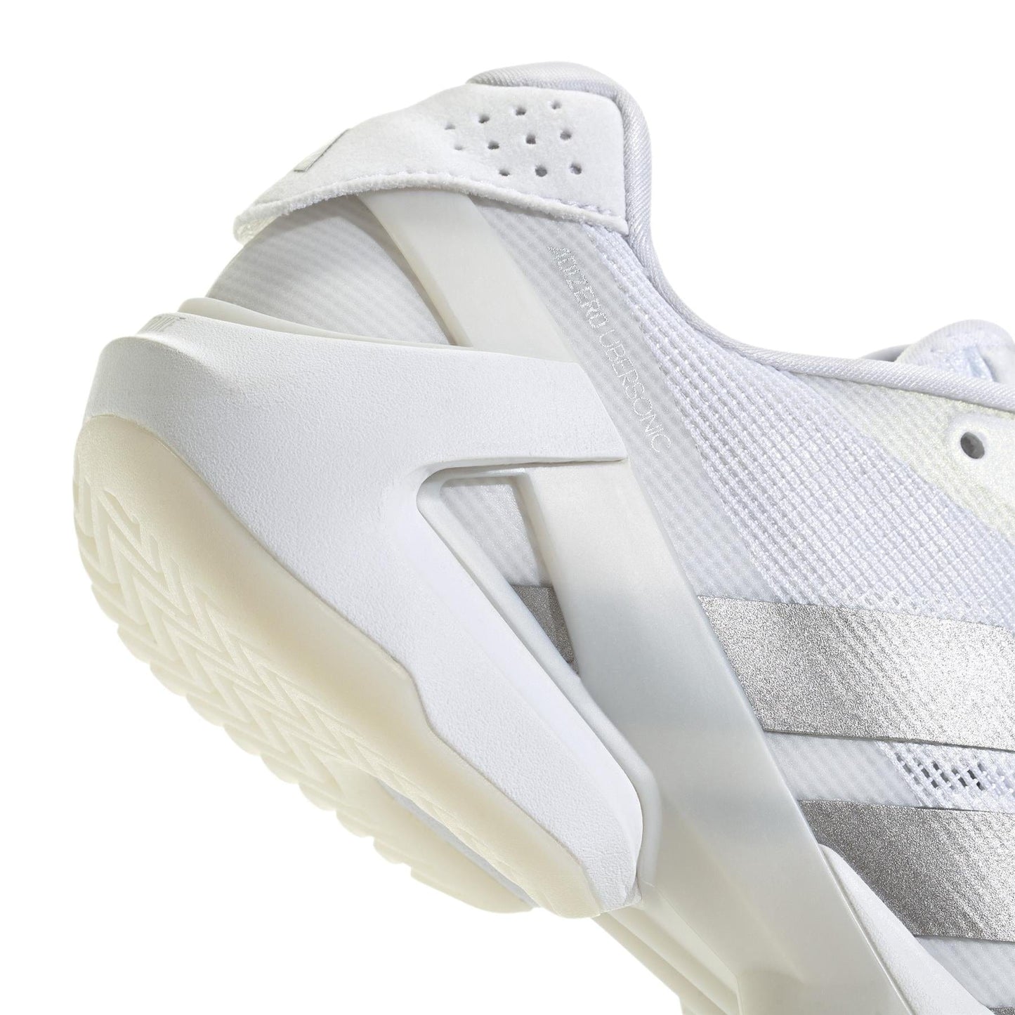 Close-up of a women's tennis shoe with a lightweight mesh upper and unique geometric heel design, featuring silver stripes. The translucent sole with textured grip enhances the sporty vibe. This modern sneaker fits perfectly into the ADIDAS Adizero Ubersonic 5 Women's Tennis Shoes collection.