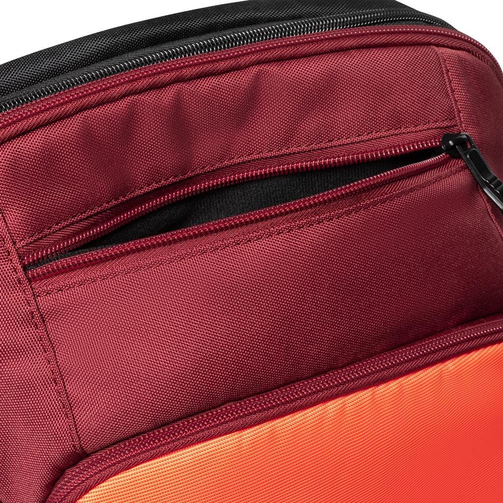 Close-up of the Dunlop CX Performance Tennis Backpack in black and red, featuring a zippered pocket with a sleek black zipper pull. The contrasting orange bottom enhances the sturdy design, making it perfect for carrying rackets and gear.