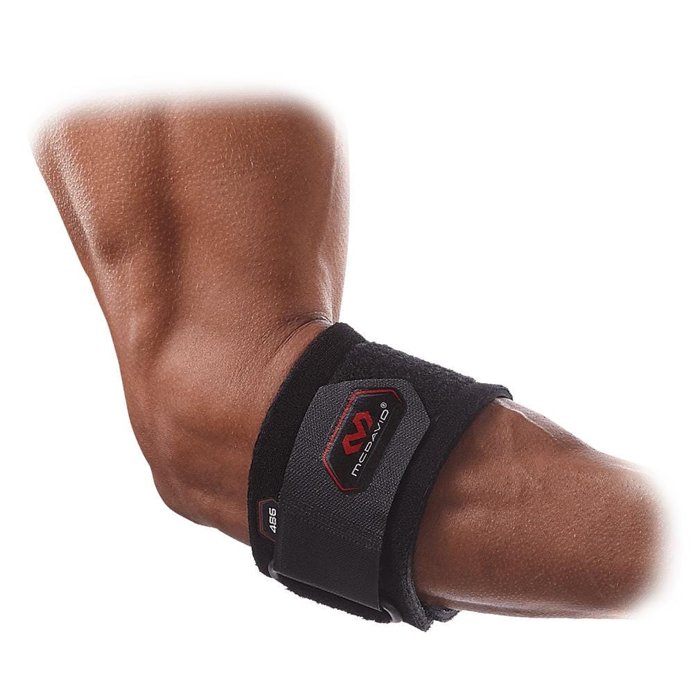 A close-up image of a person's arm wearing the McDavid Adjustable Tennis Elbow Strap, featuring a red and gray logo from the McDavid brand. This black neoprene strap offers support by encircling the forearm just below the elbow, with an adjustable design for optimal tendon pressure.