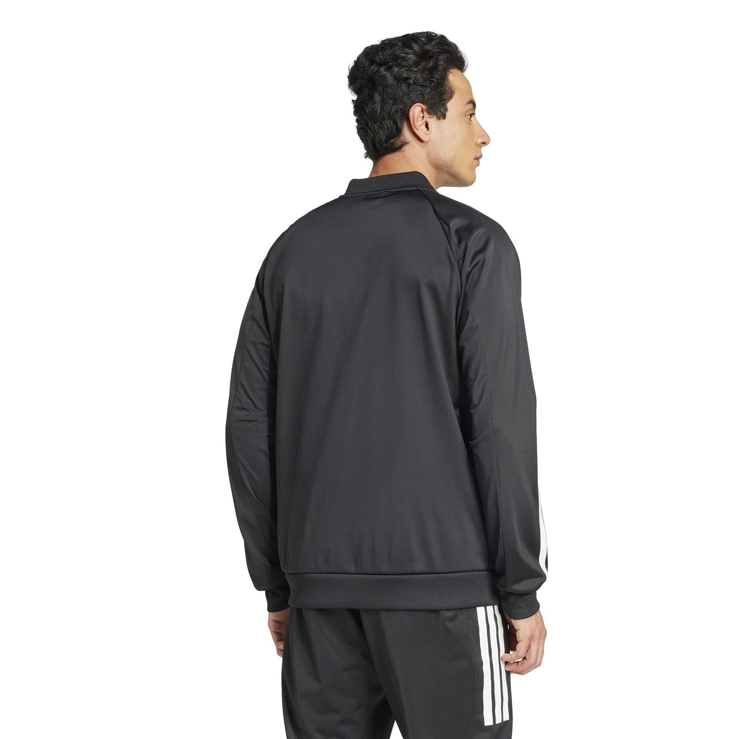 A person with dark, curly hair faces away from the camera, wearing an ADIDAS Men's 3 Stripe Knit Tennis Jacket - Black and matching black pants with white stripes. The background is plain white.