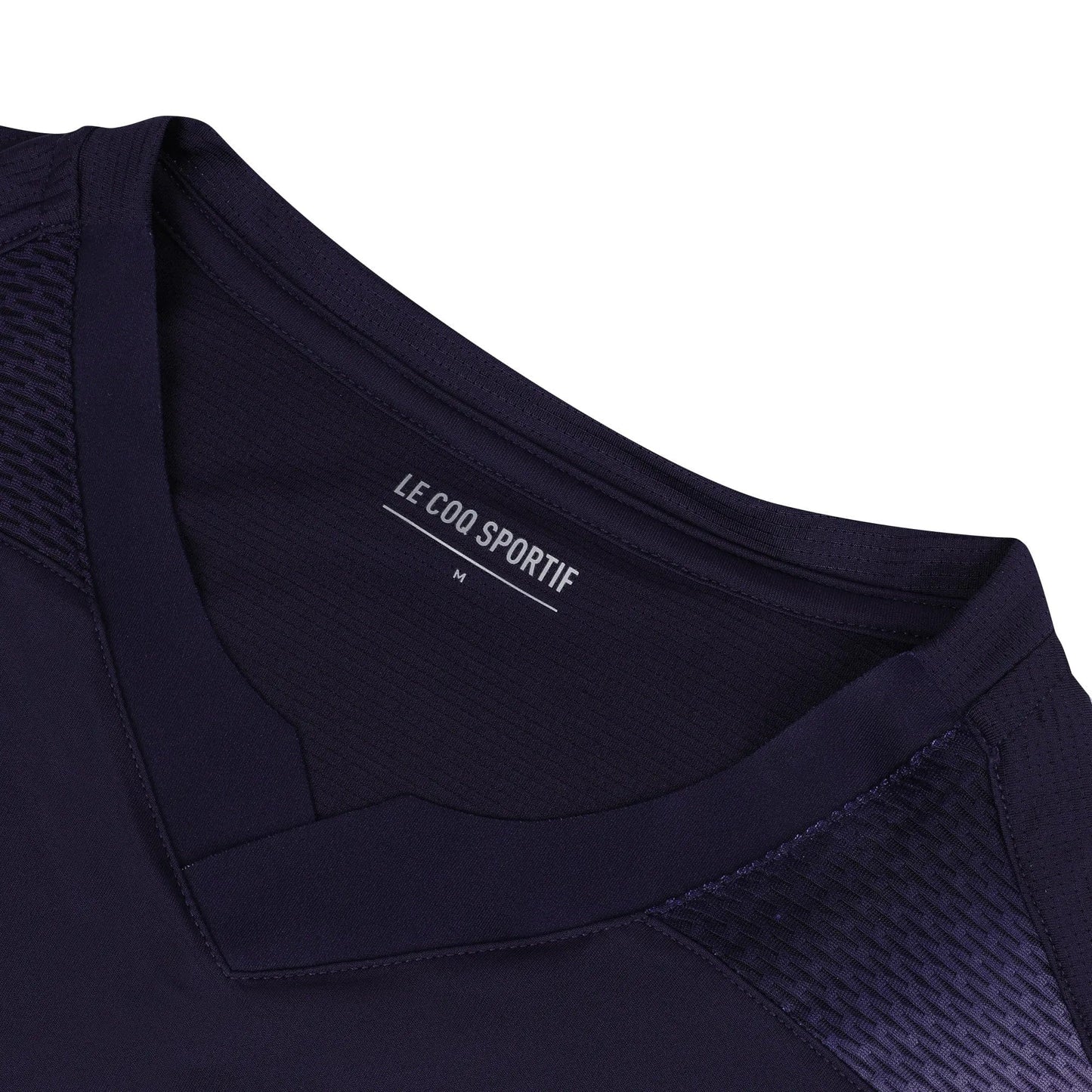 Close-up of a deep purple V-neck tennis T-shirt, crafted from breathable polyester, displaying the label "Le Coq Sportif" and size "M" on the inside collar. The shirt showcases a subtle textured pattern along the shoulders to enhance movement fluidity.