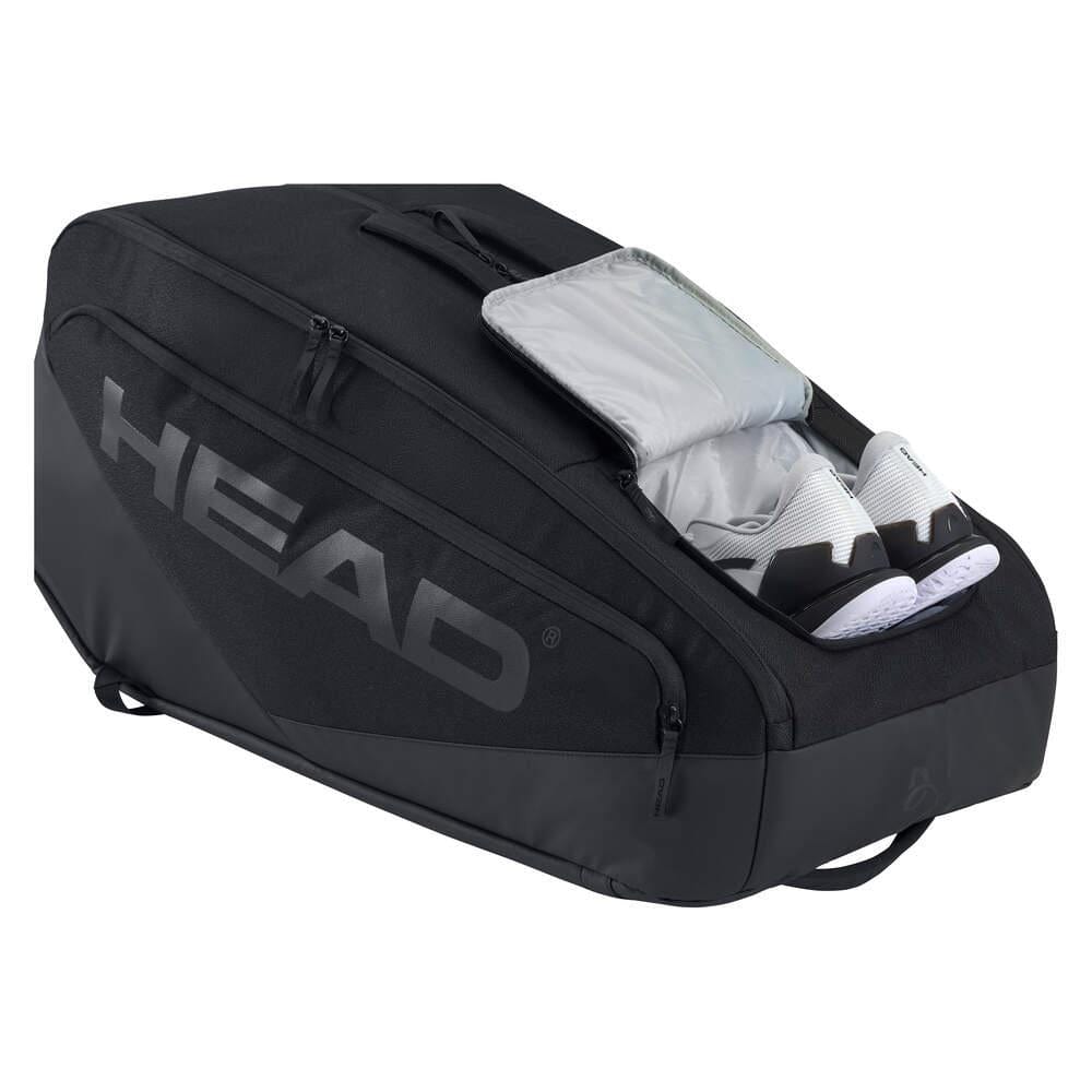 The black HEAD Pro X 12 Racket Tennis Racket Bag XL by HEAD features a zippered compartment with two white shoes partially inside. This sleek, structured bag offers several zippers for organized storage and is favored by Novak Djokovic.