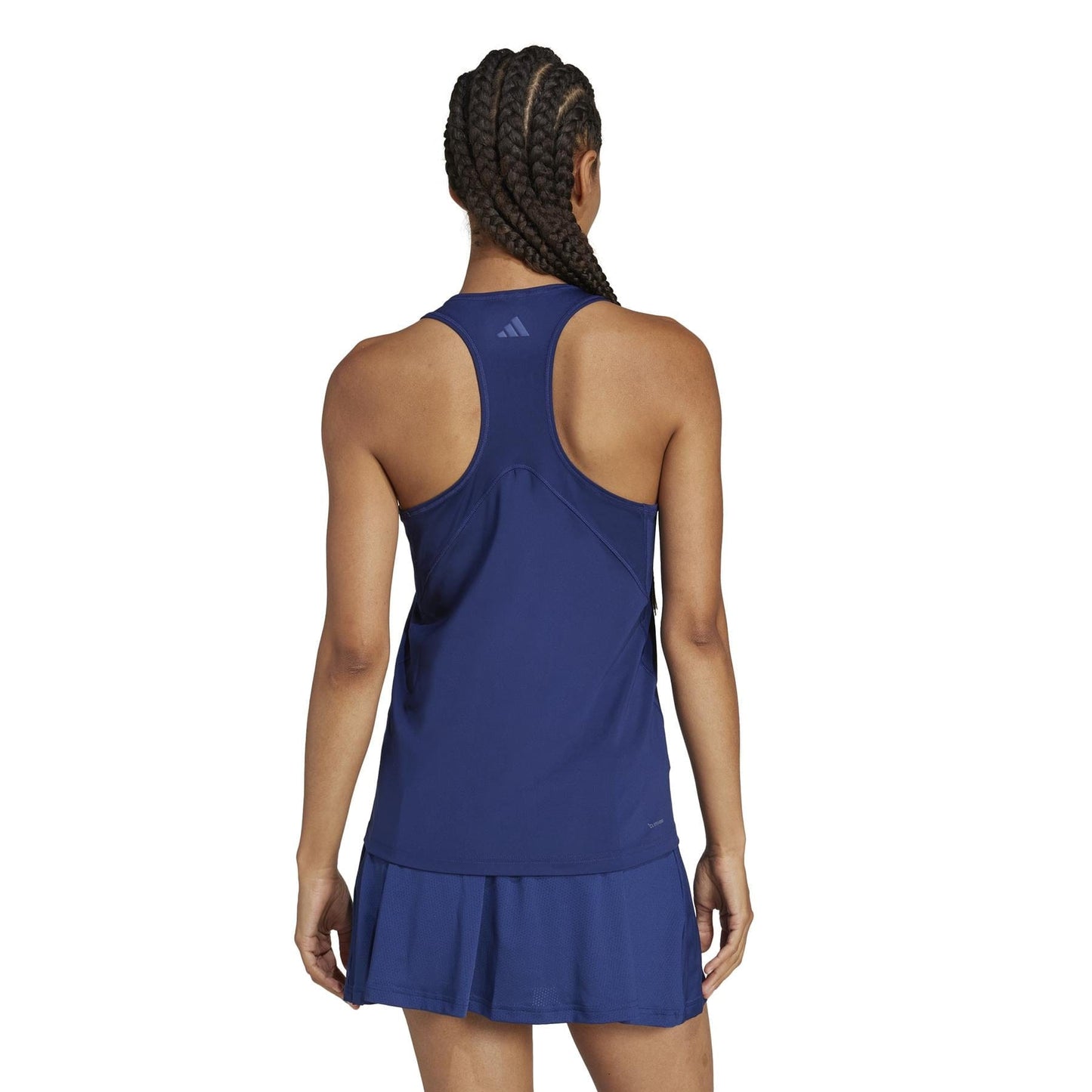 A woman with braided hair faces away, wearing the ADIDAS Women's Club Tennis Tank Top - Navy, made from recycled materials. It features Climacool technology, a racerback style, and subtle logos against a plain white background.
