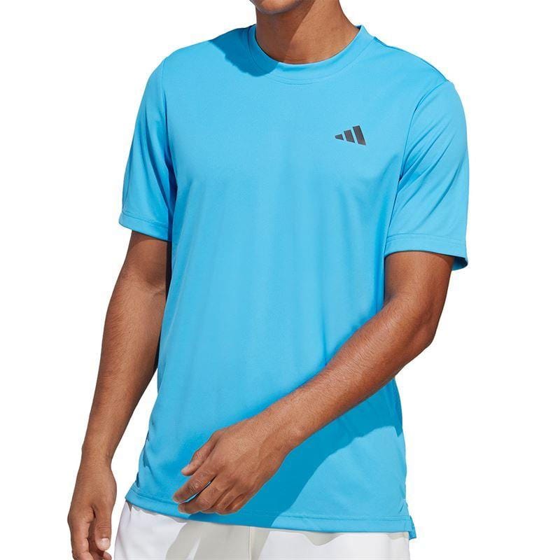 A person is wearing a Pulse Blue ADIDAS Mens Club Tennis T-Shirt by adidas, which features a logo on the chest against a plain background. This t-shirt, made with AEROREADY technology, complements white shorts for an athletic appearance.