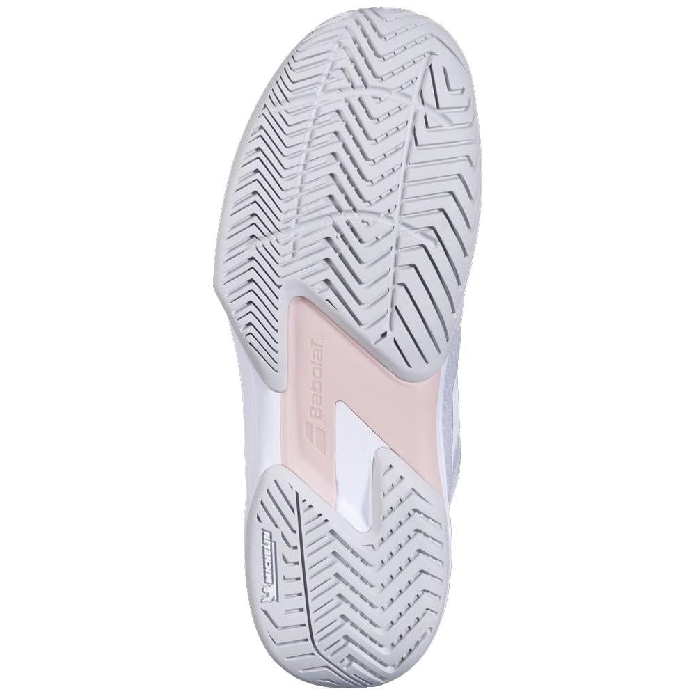The image shows the sole of a Babolat SFX 4 All Court 2025 Women's Tennis Shoe in Lunar Rock, with a white and light pink herringbone tread pattern. The brand's name and logo are prominently visible, reflecting its reputation for comfort.