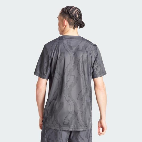 A person with braided hair is seen from the back, wearing a carbon black ADIDAS Men's Club Graphic Tennis T-Shirt and matching shorts, crafted entirely from 100% recycled materials, set against a light gray background.