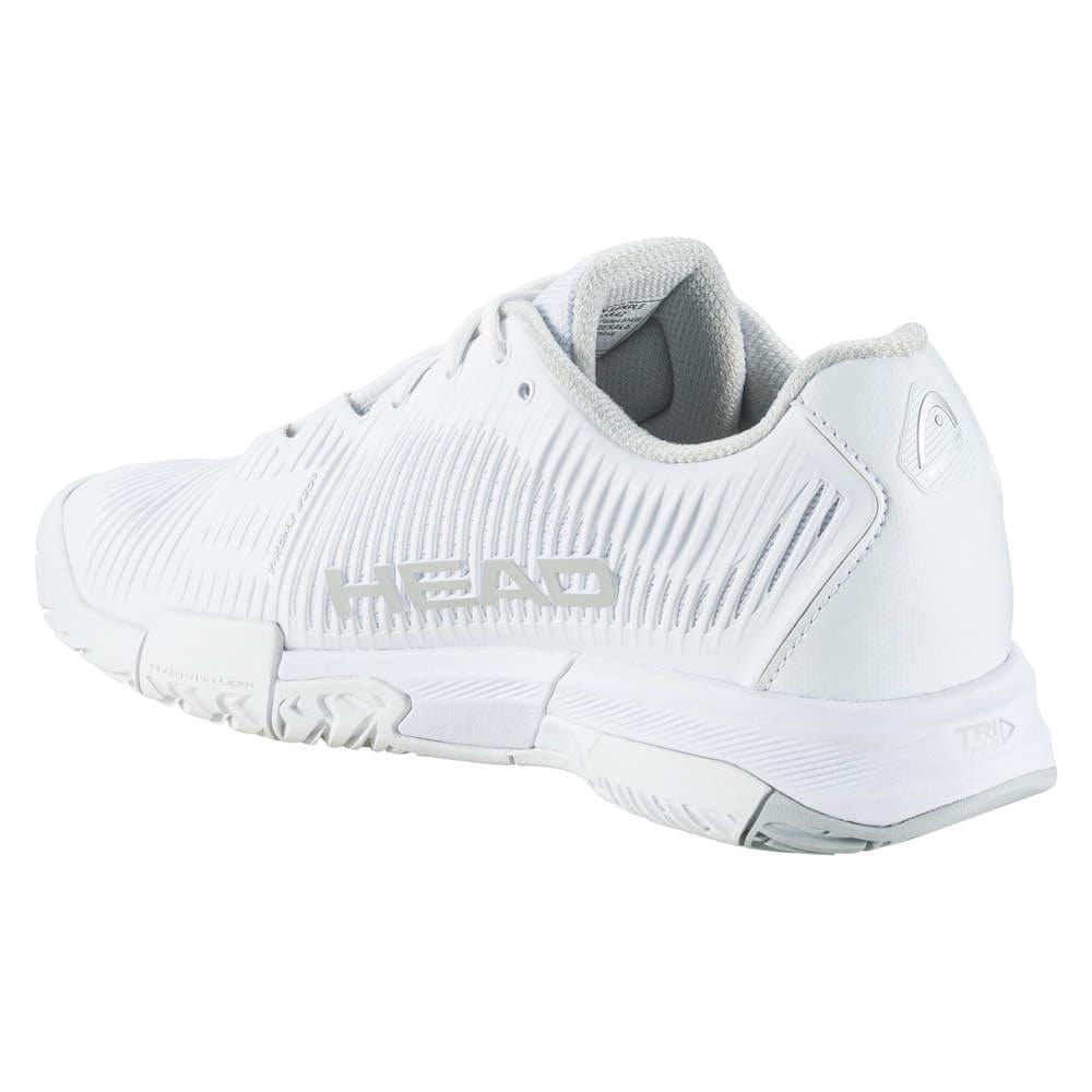 The HEAD Revolt Pro 4.0 Women's Tennis Shoes in white and grey feature textured detailing and prominently display the "HEAD" brand name on the side. Designed for sports or active use, these shoes are equipped with a rubber sole featuring grip patterns and performance technologies to improve abrasion resistance. The inner lining is a light gray shade.