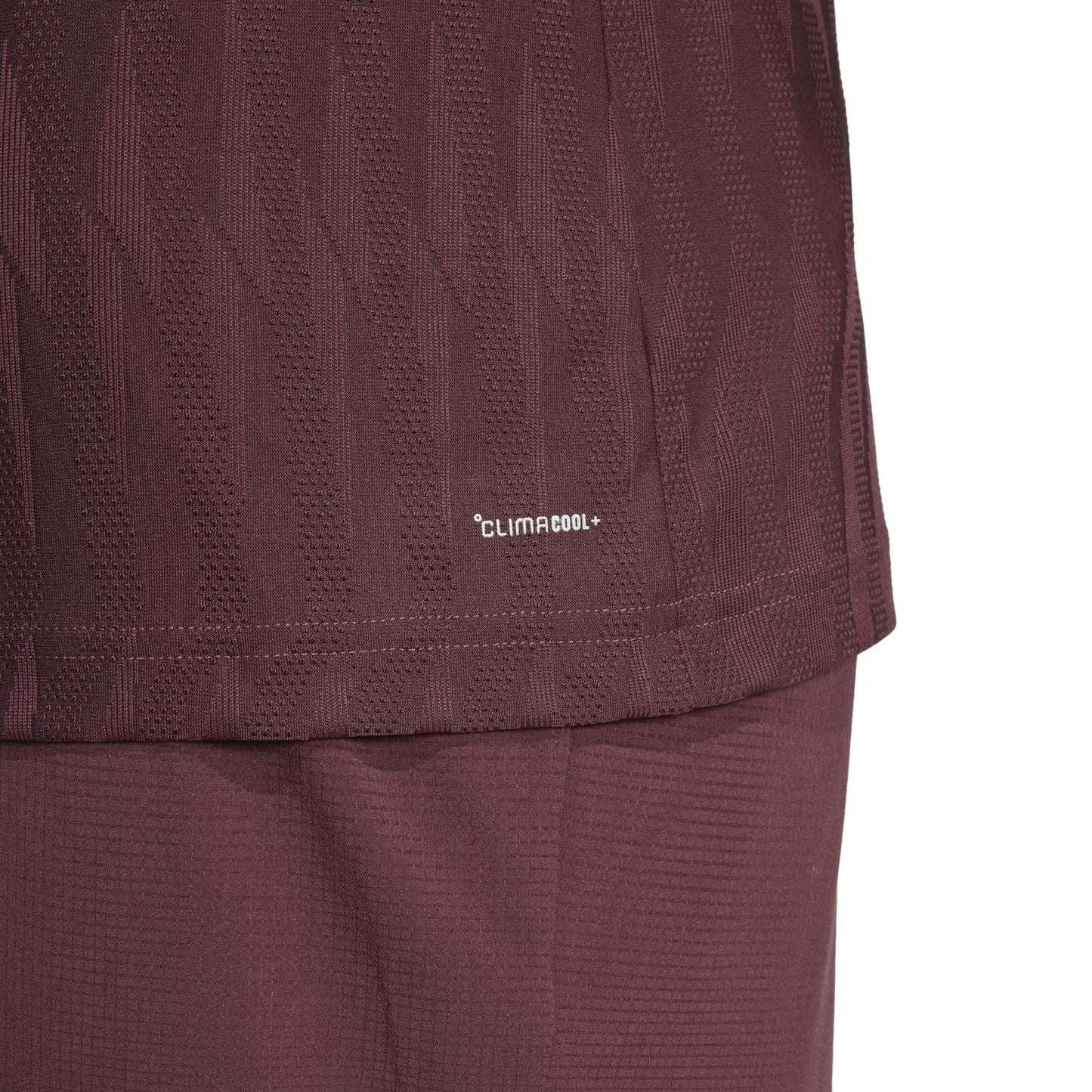 Close-up of a dark ruby adidas sports jersey crafted from recycled materials, with a subtle pattern and the "CLIMACOOL" logo near the hem. A part of matching shorts is visible below.
