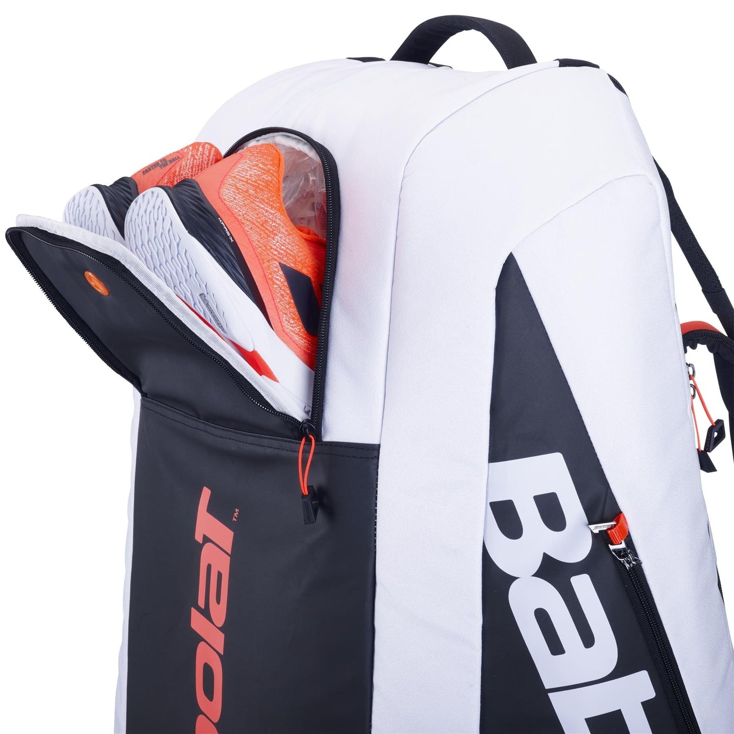 A Babolat RH12 Pure Strike 4th Gen Tennis Bag in white and black with red accents, made from recycled polyester, prominently features the "Babolat" brand name. The open compartment reveals a pair of orange and white sports shoes partially visible inside.