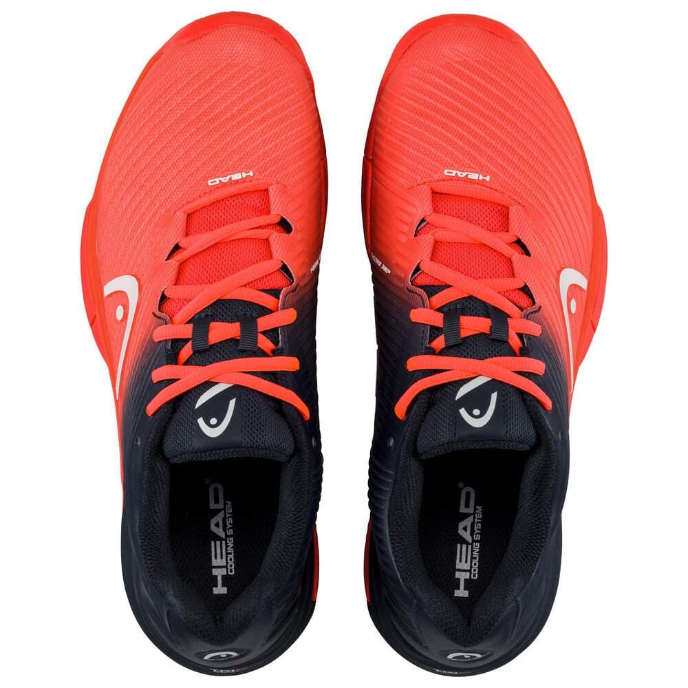 The HEAD Revolt Pro 4.0 Men's Tennis Shoes in bright orange and black showcase a sleek design with laces, infused with performance technologies. The brand "HEAD" is prominently displayed on the tongue, complemented by a small white logo on the sides, visible from an aerial perspective.