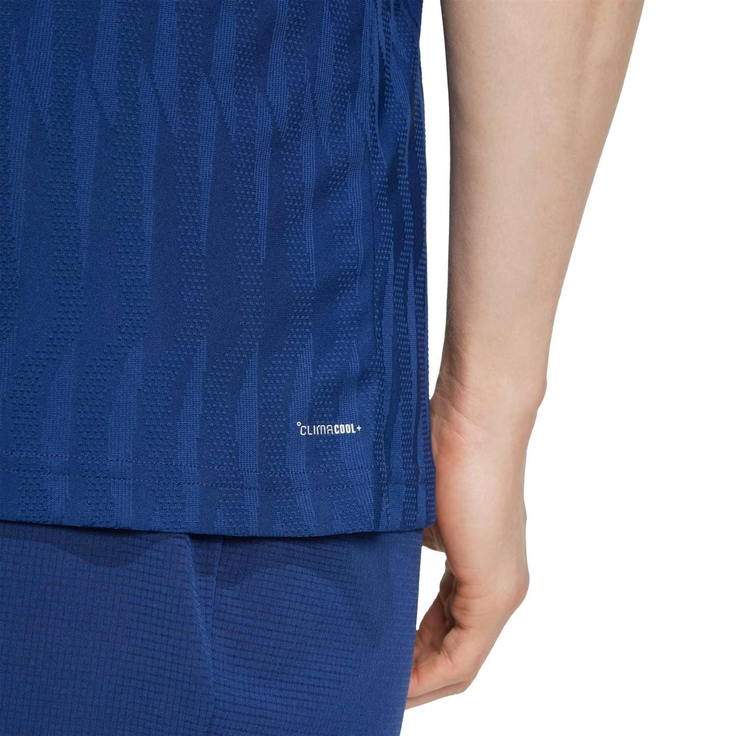 A person is wearing a navy ADIDAS Mens Climacool+ Freelift Tennis T-Shirt and shorts, featuring a subtle geometric design. The word "Climacool" appears on the side for advanced performance, with their right arm and side visible against a white background.