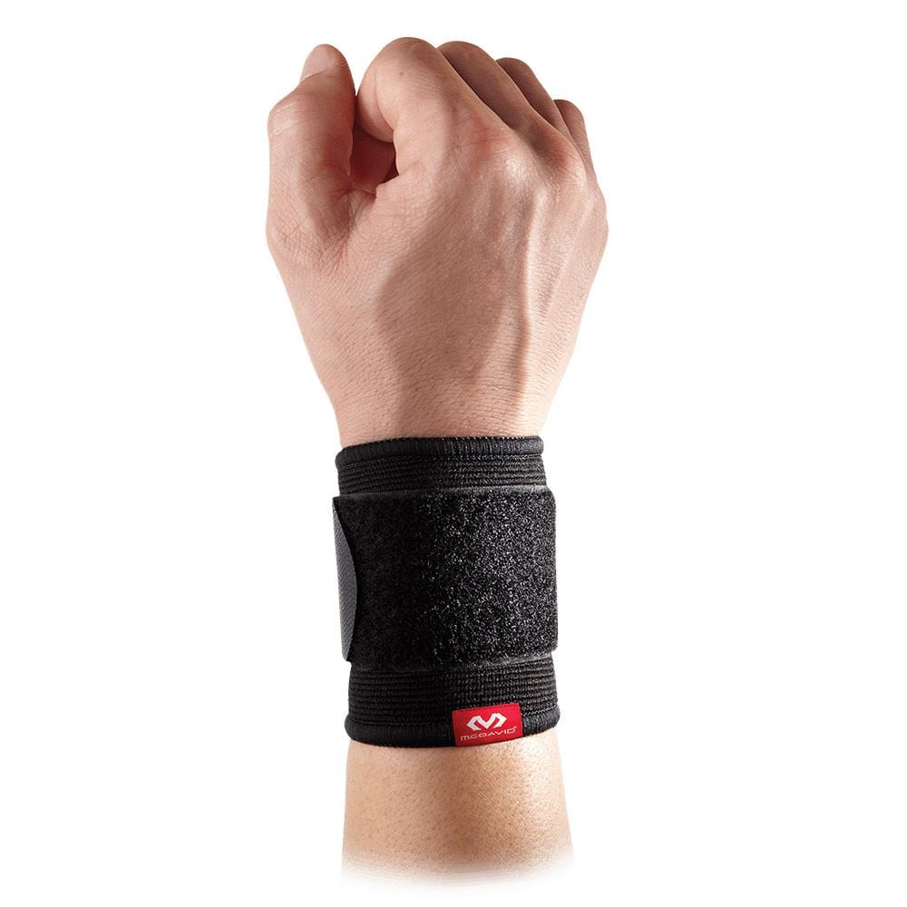 A hand is raised wearing the McDavid Adjustable 2-Way Elastic Wrist Sleeve in black, which showcases an adjustable strap and a small red McDavid logo at the bottom. The breathable elastic material ensures comfort, all set against a crisp white background.