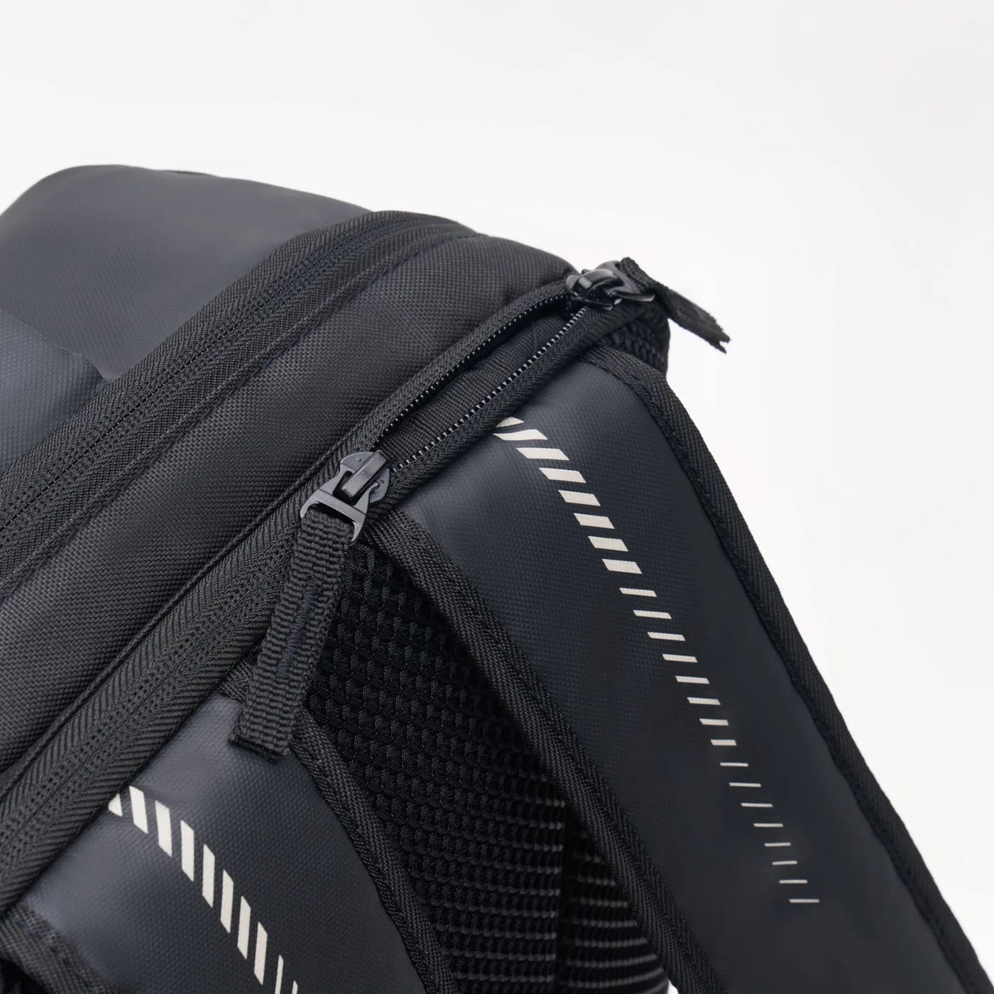 Close-up of the Kanso Intuko Tennis 23L Backpack - Black, an everyday companion with two main compartment zippers and a padded shoulder strap featuring a white-striped design. Its modern look is enhanced by textured material on the strap's underside.