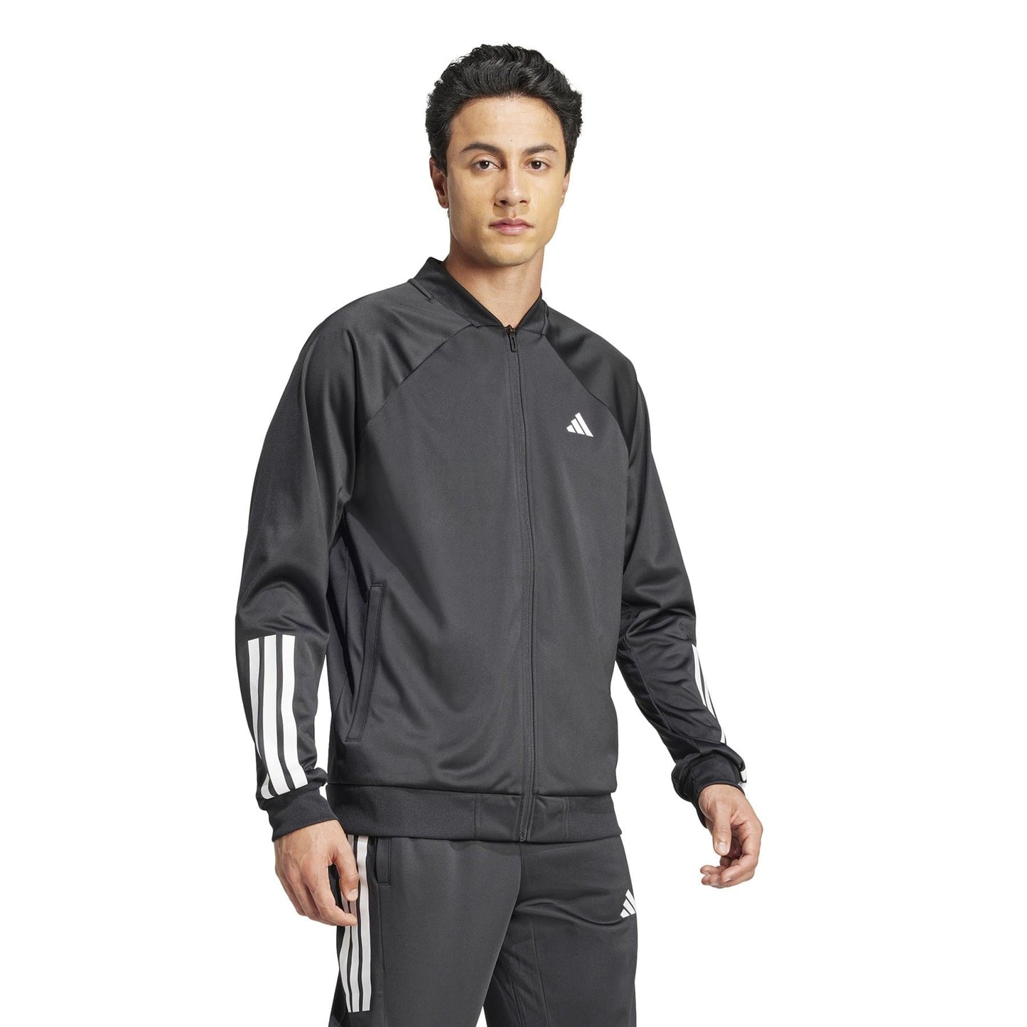 A person dons an ADIDAS Men's 3 Stripe Knit Tennis Jacket - Black, paired with matching pants, against a white backdrop. The jacket highlights the signature three stripes on the sleeves and the adidas logo on the chest.