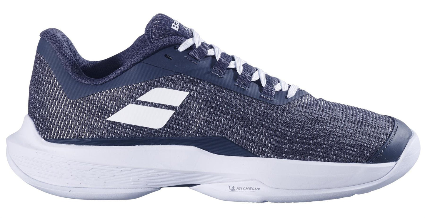 Side view of a Babolat Jet Tere 2 2024 women's tennis shoe in Queen Jio Grey with white accents, featuring a mesh upper, white laces, and a thick white sole bearing the Michelin logo. This ultra-lightweight shoe ensures comfort and stability with two white side stripes and branding on the tongue.