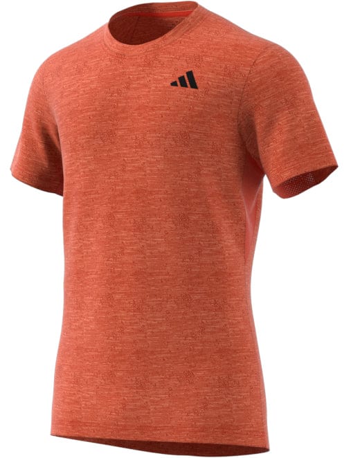 The red short-sleeve athletic T-shirt, shown on a white background, is the adidas Men's Freelift Tennis T-Shirt. It includes a small black logo on the left chest and has AEROREADY cooling fabric for a comfortable, fitted design perfect for exercise.