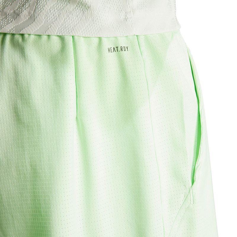 Close-up of a light green athletic skirt featuring a subtle perforated texture and crafted from recycled materials. The waist displays the text "HEAT.RDY" in small black letters, reminiscent of the ADIDAS Melbourne Men's 2in1 Tennis Shorts by adidas.