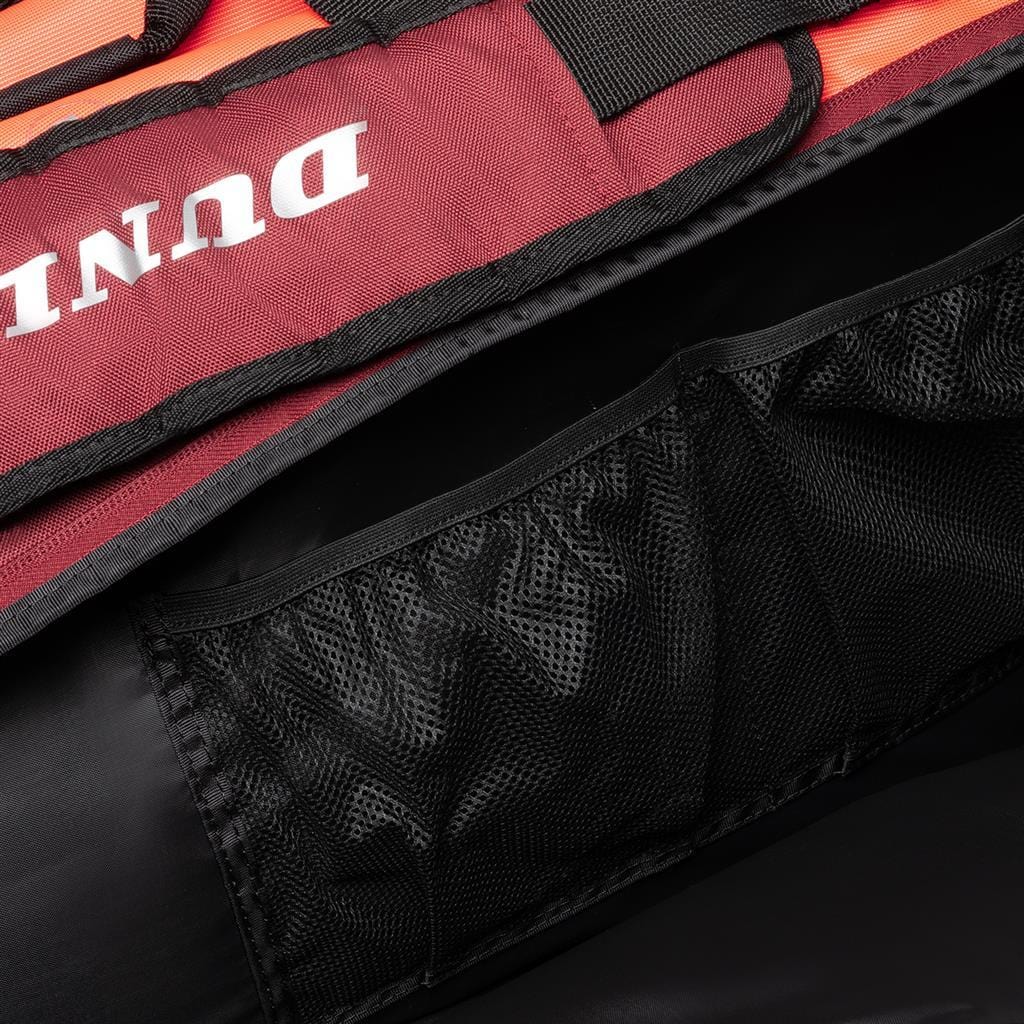 A close-up of the black mesh pocket inside a black and red Dunlop CX Performance 12 Tennis Racket Bag, shown at a diagonal angle. The ventilated shoe compartment promotes breathability, while the mesh accentuates its texture and utility for storing items.