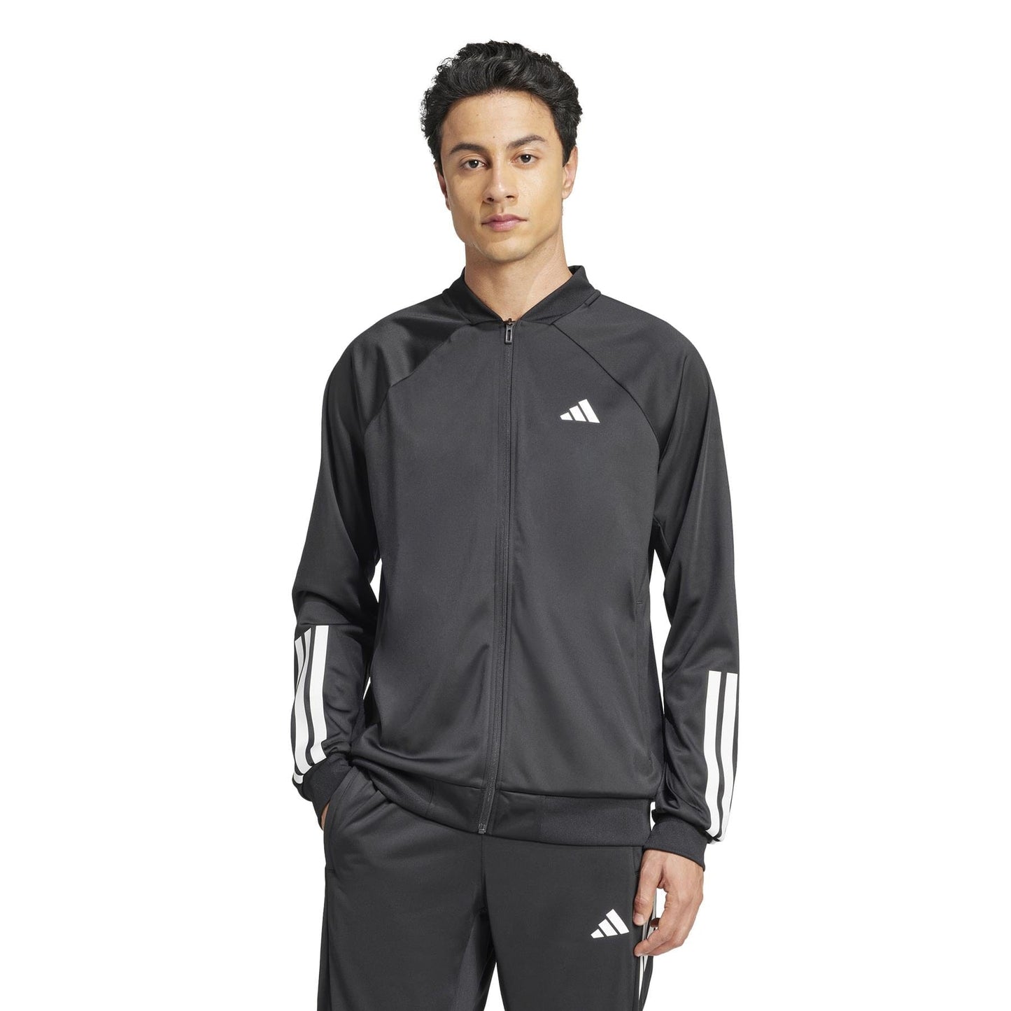 A person with short dark hair stands against a white background wearing an adidas Men's 3 Stripe Knit Tennis Jacket in black, featuring the iconic logo on the chest.
