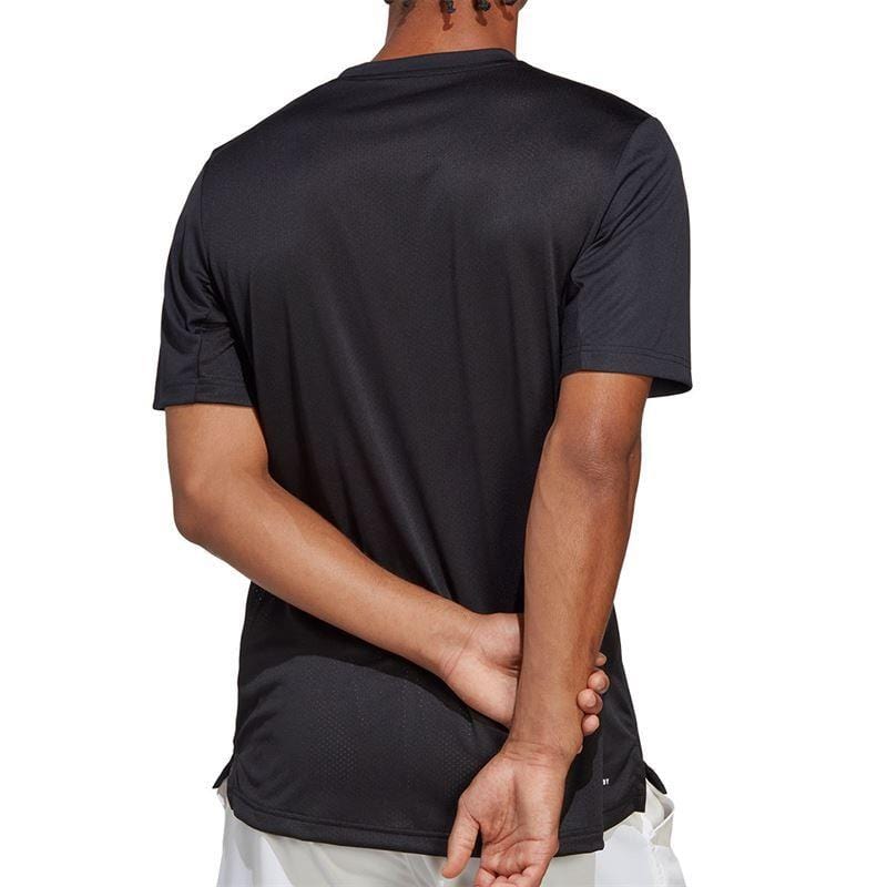 A person wearing an ADIDAS Men's Club Tennis T-Shirt in black and white shorts stands with their back to the camera, hands clasped behind them. The crisp background highlights the sleek design of adidas's AEROREADY attire.