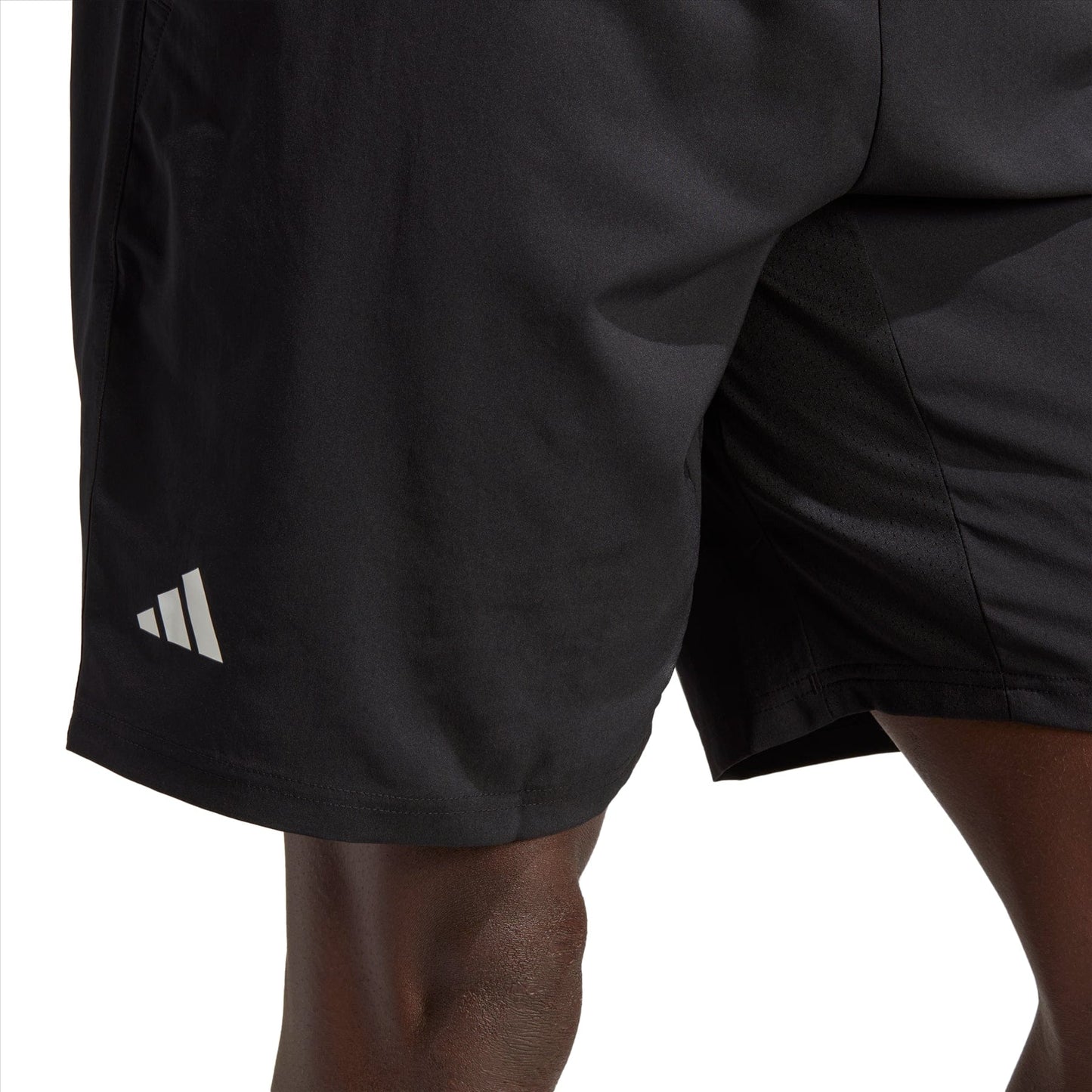 Close-up of a person wearing black adidas Club 3 Stripe 7" Men's Tennis Shorts, featuring the iconic white logo on the left side. Made from recycled materials, these shorts prioritize comfort and flexibility, while the moisture-wicking fabric keeps you dry during intense workouts. The background is plain white.
