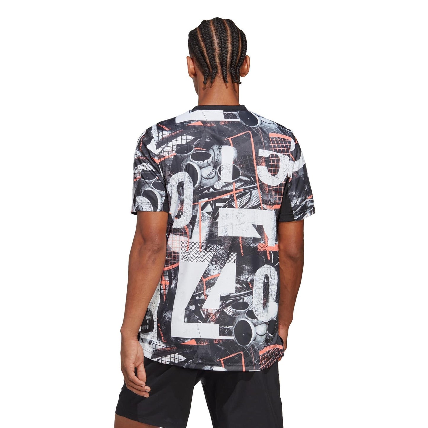A person with braided hair is donning an adidas Club Men's Graphic Tennis T-Shirt, which showcases abstract designs and numbers in a palette of black, white, and red. Crafted from recycled polyester and equipped with AEROREADY moisture-wicking technology, they are also wearing black shorts while standing against a plain white background, with their back turned to the camera.