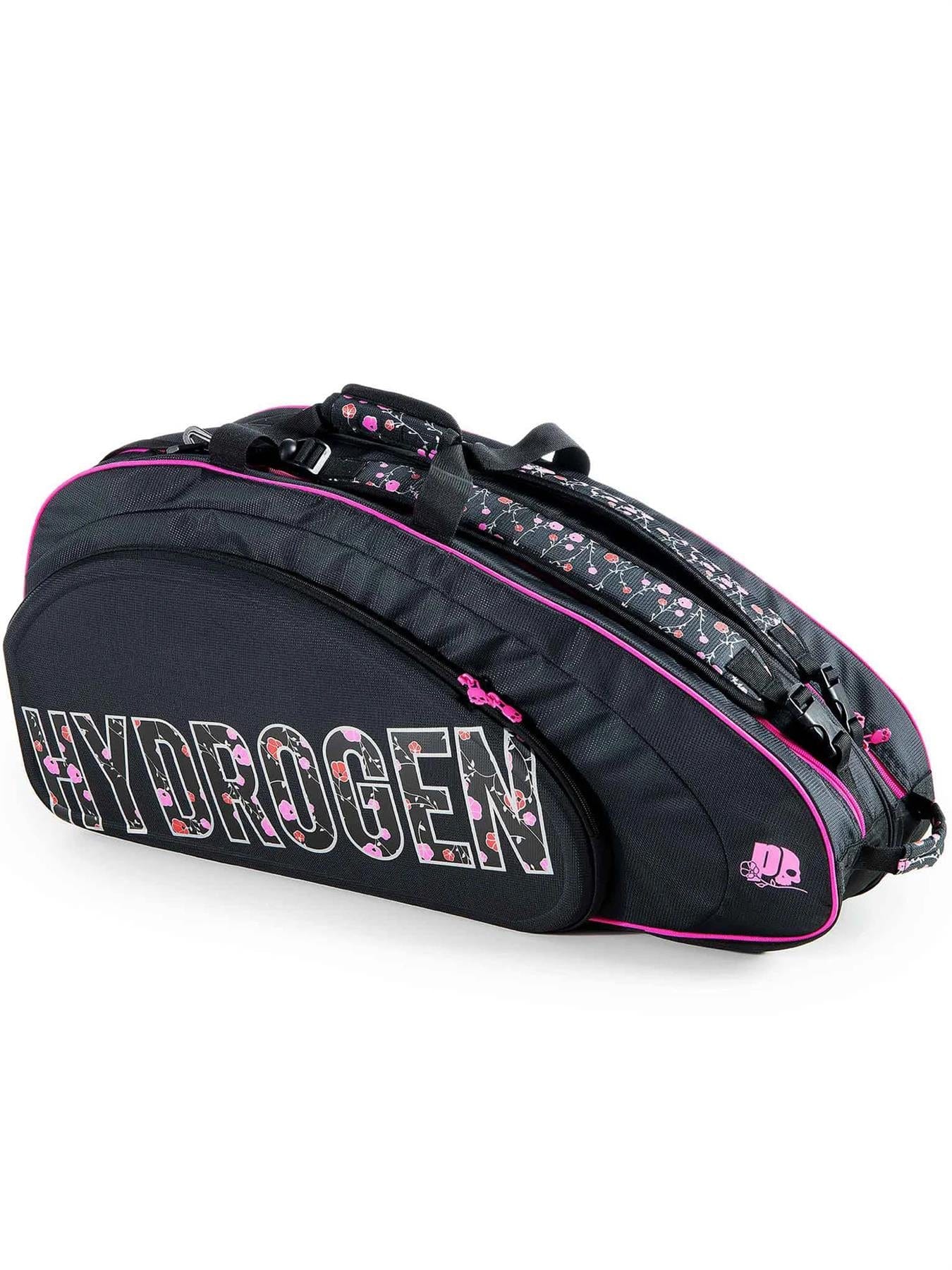 The Prince Hydrogen Lady Mary 6 Racket Tennis Bag in black and pink, adorned with "HYDROGEN" lettering, offers ample space for up to six rackets. Its numerous compartments and zippers, along with the elegantly designed floral handles, make it a stylish choice.