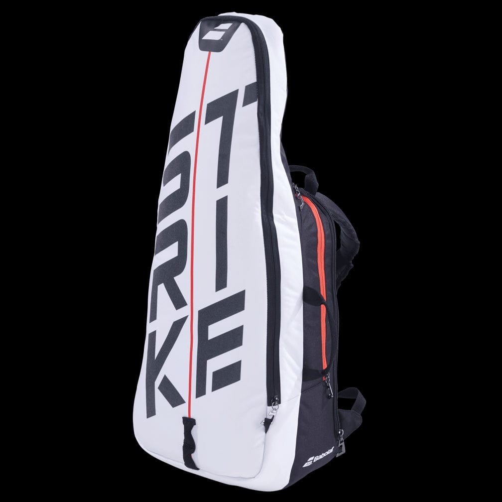 The Babolat Pure Strike Tennis Backpack in white and red is a stylish tennis racket bag that showcases bold text and an eye-catching red line design. It includes specialized compartments, such as an isothermal insulated section for your tennis gear, and features a convenient top handle for easy transport.