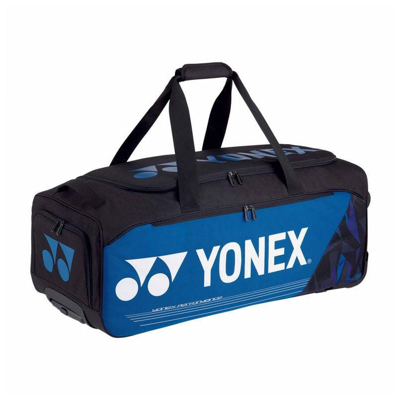 Introducing the Yonex 92232EX Pro Trolley Bag in Fine Blue, a chic black and blue duffel featuring multiple compartments. Ideal for professional tour players, it proudly displays the iconic Yonex logo and is crafted to effortlessly carry all your essential sports gear.