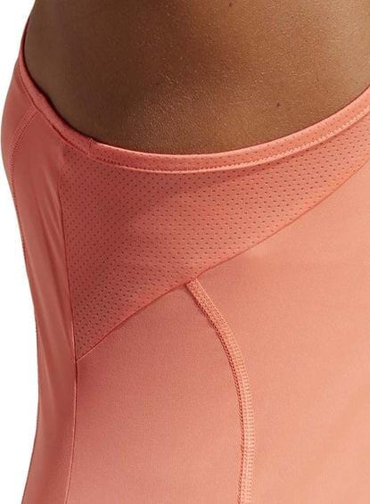 Close-up of a person wearing the adidas Women's Club Tennis Dress in coral, showcasing its mesh detailing on the sides that emphasizes the texture and seam design. Crafted with adidas Primegreen materials, this elegant piece combines comfort and sustainability for an active lifestyle.