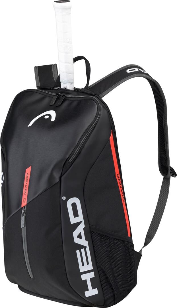 The HEAD Tour Team Tennis Backpack in Black and Orange features zippered compartments, including a dedicated shoe compartment. Mesh side pockets enhance its design as a tennis racket with a white grip protrudes from the top, showcasing the bag's functional racket compartment.