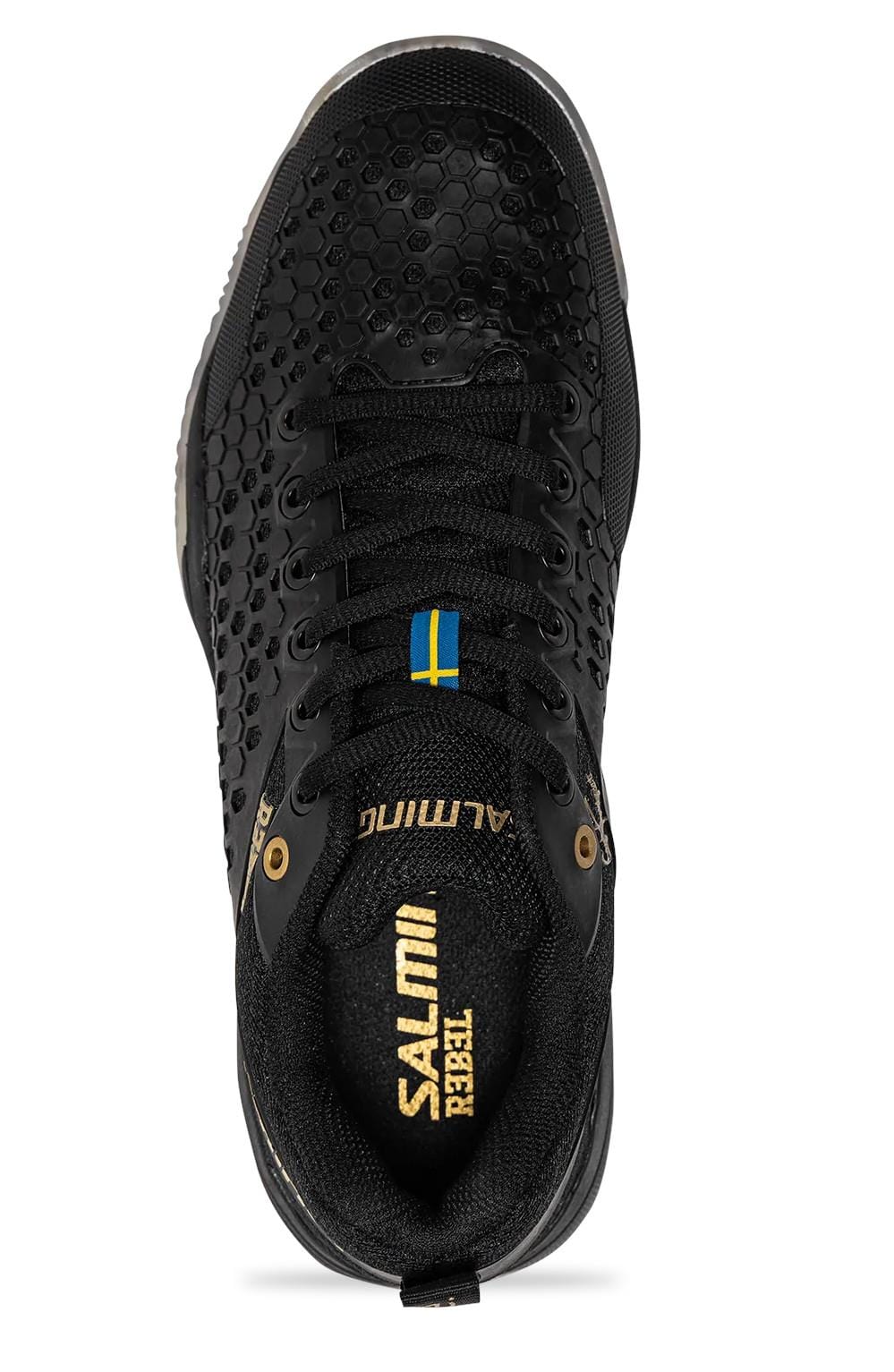 From a top-down perspective, the Salming Rebel Mens Indoor Court Shoe in black and gold showcases a stable sneaker design with a textured honeycomb pattern and sleek gold accents. The tongue features a small blue and yellow flag, while "Salming Rebel" is prominently displayed on the upper for added style and optimum grip on the court.