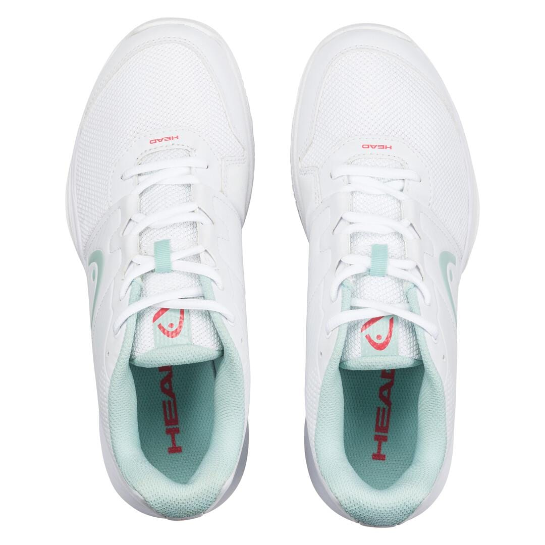 Top view of the HEAD Revolt Court women's tennis shoes in white and grey. These lightweight shoes feature a mesh texture for breathability and have "HEAD" printed in red on the tongue and inner sole, providing comfort both on and off the court.
