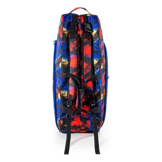 A vibrant Prince Hydrogen Random 9 Racket Tennis Bag, adorned with abstract red, blue, and multicolored patterns, stands upright on a white background. It showcases its black straps and handles and features adjustable shoulder straps for comfort and versatility.