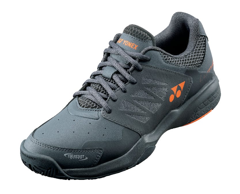 The Yonex Power Cushion Lumio 3 All-Court Men's Tennis Shoes in Dark Gun feature a dark gray color with orange accents, designed with a mesh upper for breathability and a thick sole for support. Ideal as all-court tennis shoes, they include a lace-up design and display visible brand logos on the side and tongue, showcasing Yonex's Power Cushion technology.