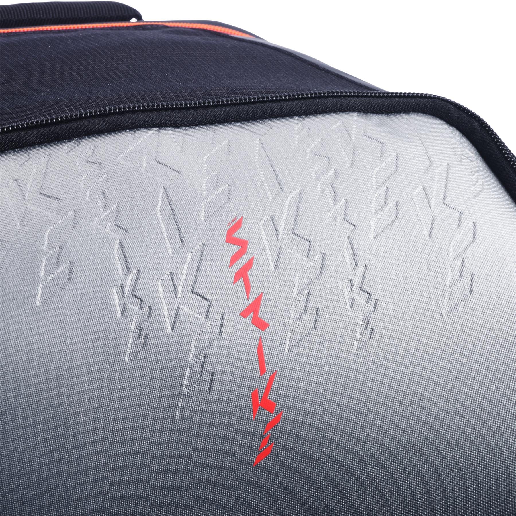 Close-up of the textured carbon grey and black surface of the Babolat Pure Strike Tennis Backpack, featuring embossed patterns and a central vertical line of red symbols.