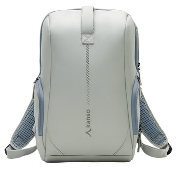 The Kanso Intuko Tennis 23L Backpack in gray is a sleek, minimalist accessory featuring blue mesh side pockets, padded shoulder straps, and a discreet racket compartment. It has reflective print, a vertical design element, and the brand name "Kanso," embodying modern style.