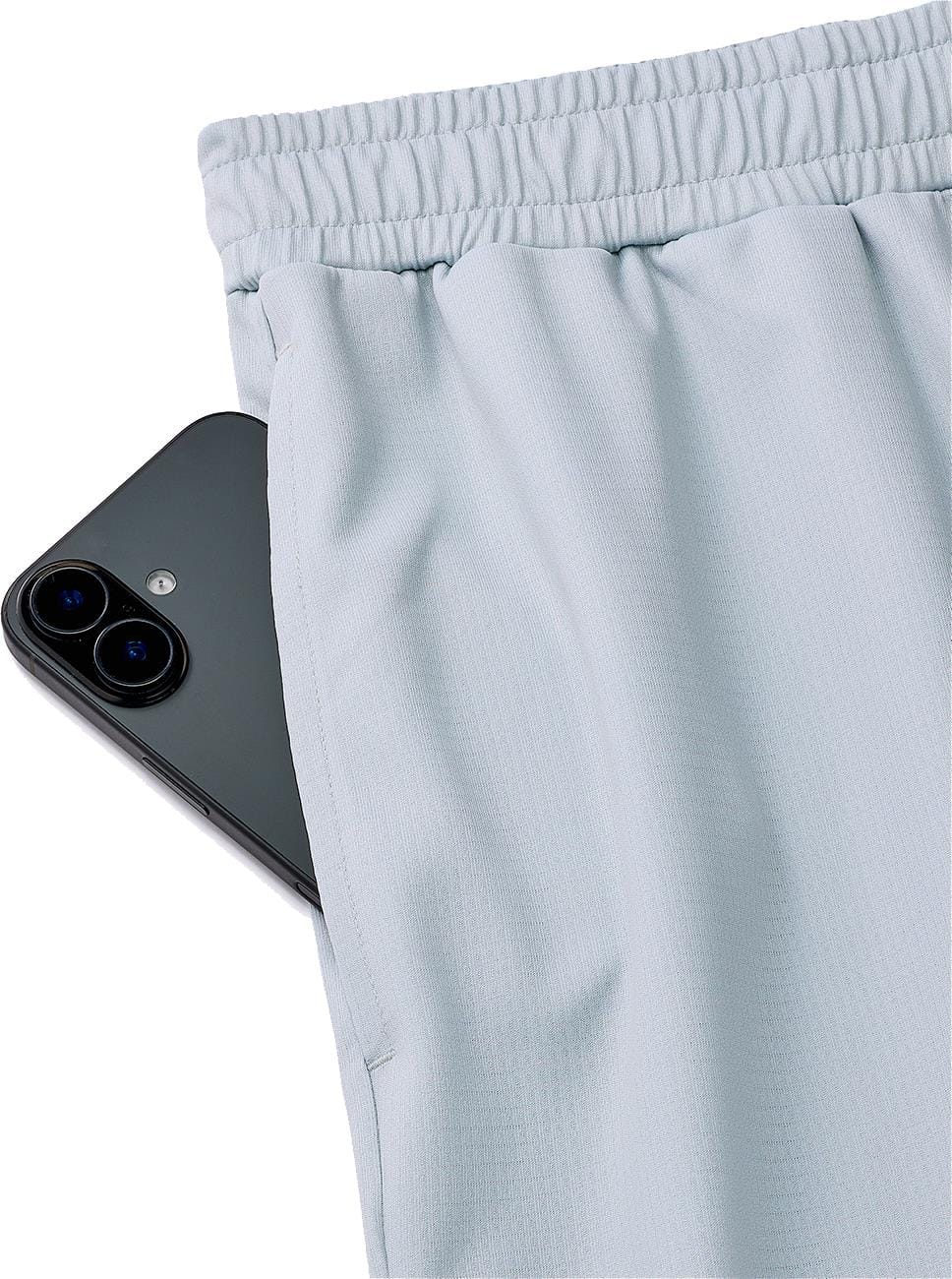 A black smartphone is partially tucked into the pocket of Yonex 15241EX Knit Men’s Tennis Shorts in Silver Grey, featuring moisture-wicking fabric and an elastic waistband.