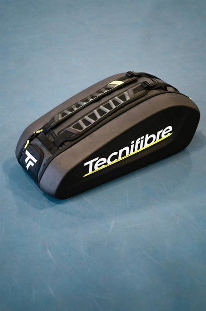 The Tecnifibre Reform L Tennis Racket Bag - Black, made from durable EVA material, features carrying straps and the Tecnifibre logo on the side. Its spacious design with yellow and white accents sits on a blue surface.