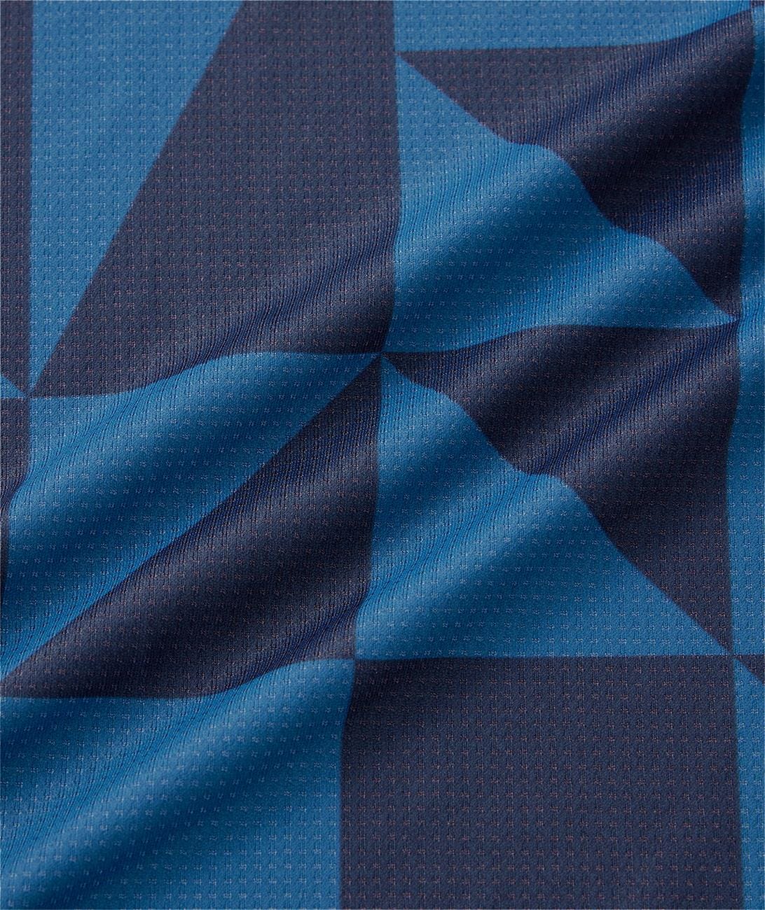 The Yonex 10712YX Crew Neck Men’s Tennis T-Shirt in Indigo Blue features dark and light blue geometric patterns with diagonal folds, subtle dotted texture, and shadowed blocks for optimal sports performance.