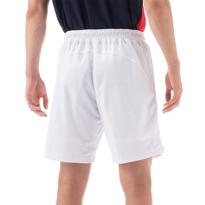 A person wearing a navy and red shirt with Yonex 15131 Mens Shorts in white stands facing away. The performance shorts from Yonex feature an elastic waistband, and their arms are relaxed at their sides against a plain white background.