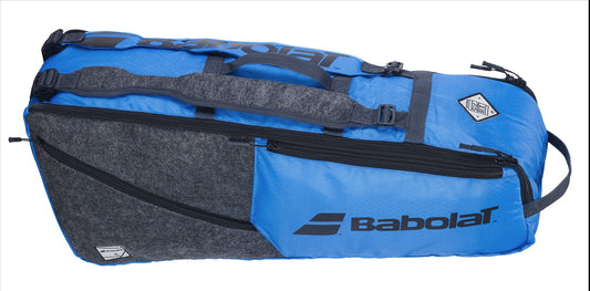 The Babolat RH6 Evo Drive Tennis 6 Racket Bag in Blue and Grey showcases black and gray accents. This bag, designed to hold up to six rackets, includes a spacious zippered compartment, convenient shoulder straps, and a small side pocket featuring the logo and design markings.