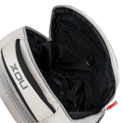 The NOX Pro Pickleball Backpack - Cream by NOX features a spacious black interior with a zippered pocket, key holder clasp, and ergonomic padded straps. The partially unzipped bag reveals its sleek inside lining for easy access and organized carrying.