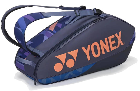 The Yonex 92426EX 6 Racket Pro Tennis Bag in Midnight Navy features orange branding, geometric blue side patterns, two shoulder straps, and holds up to six rackets—combining style and function for tennis players.