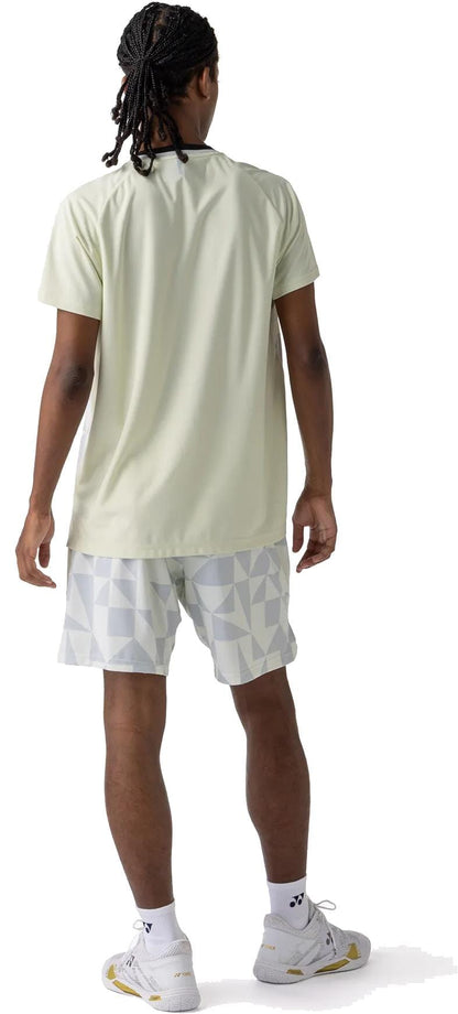 A person with braided hair faces away, wearing the Yonex 10712YX Crew Neck Men's Tennis T-Shirt in Champagne, patterned white shorts, white socks, and white sneakers—ideal for a sporty look.