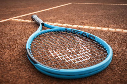 The HEAD Boom MP 2026 Tennis Racket, known for its explosive power, rests on the clay court near the white boundary lines.