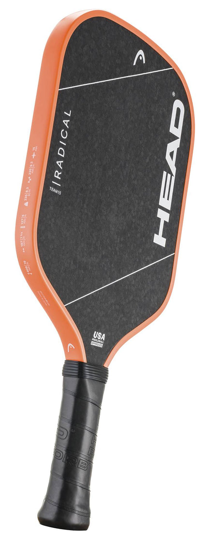 The HEAD Radical Team 15 2026 Pickleball Paddle features an orange edge, a black face with white branding and text on the face and side, as well as a black grip. It is equipped with a TriFlex core for enhanced performance.