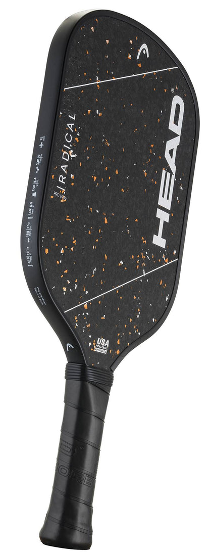 A HEAD Radical Pro EX15 2026 pickleball paddle in black with orange speckles, featuring a raw carbon surface and a black grip handle, is shown on a white background.