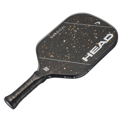 The HEAD Radical Pro 15 2026 Pickleball Paddle features a sleek black design with a raw carbon surface accented by orange flecks. The word "HEAD" is boldly printed in large white letters, while "RADICAL" appears on the upper side. Equipped with the advanced TriFlex Versatility Core technology, this paddle includes a handle wrapped in black grip tape for maximum comfort and control.